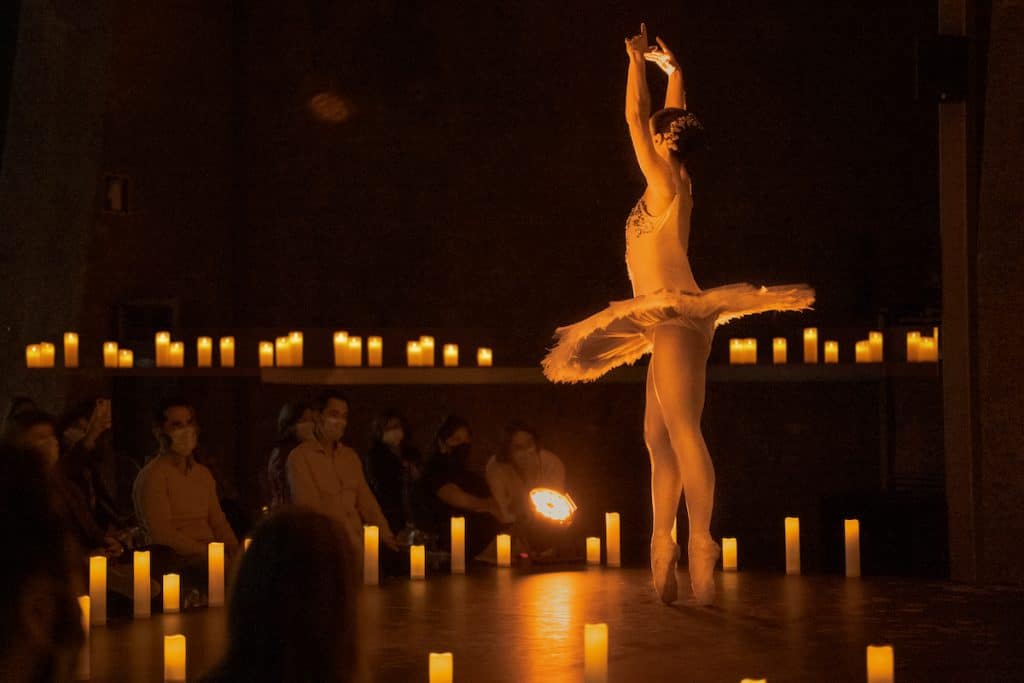 Ballerina dances in front of crowd among candlelight