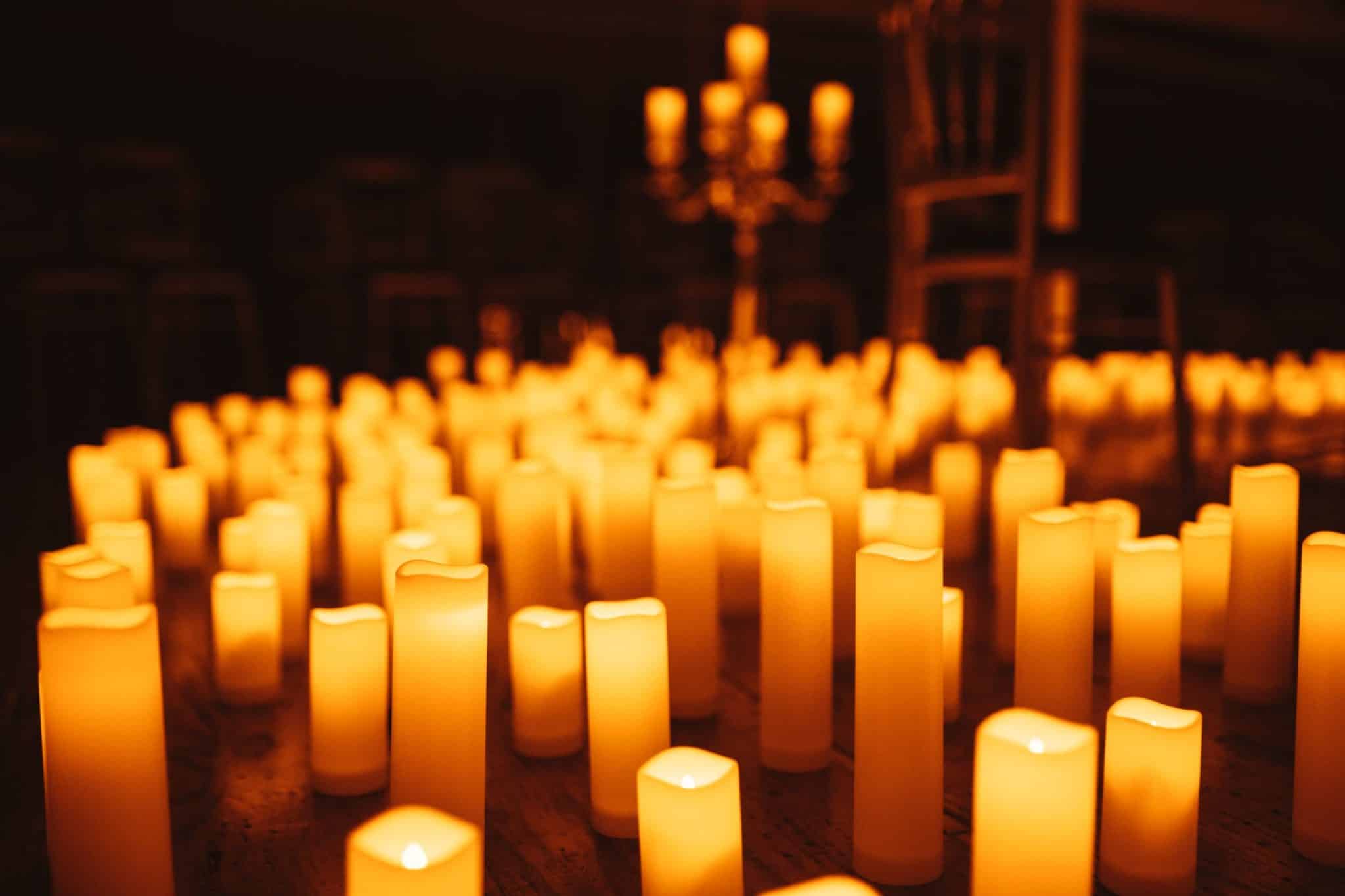 A close-up of candles on the ground with a tall candelabra in the background. 