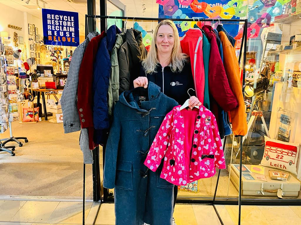 Sara-Thomson-founder-of-The-Clydeside-Collective-holding-coats-with-rail-behind
