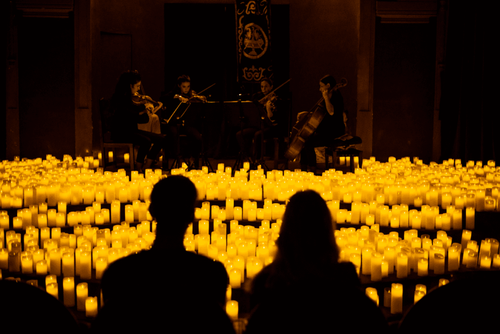 A string quartet performing to an audience surrounded by a sea of candles