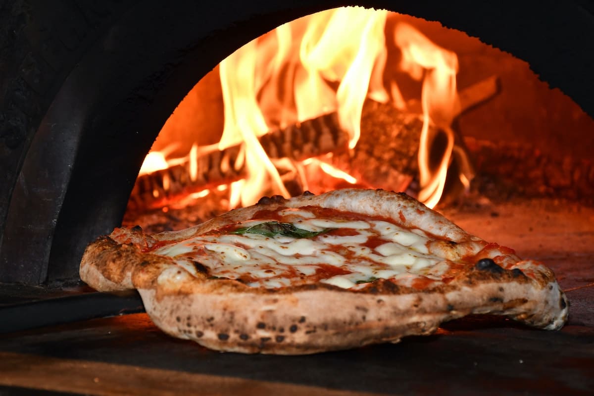 pizza coming out of woodfire oven
