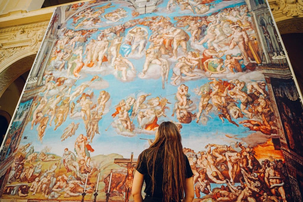 a woman looking up at the sistine chapel artwork