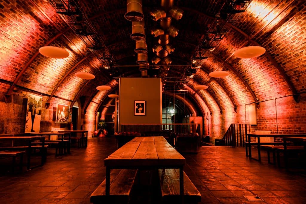 A long table is in the middle of the photograph under an arched ceiling in an industrial-style underground space.
