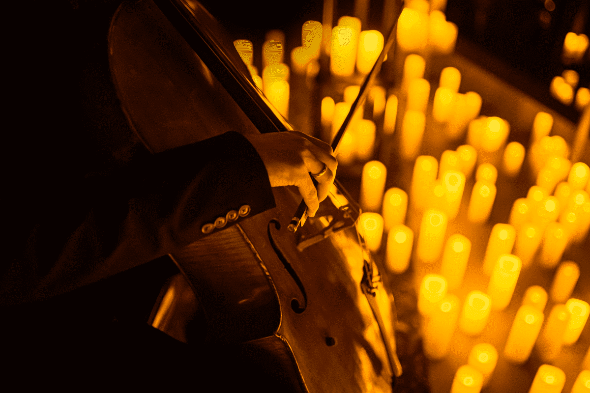 Person playing a cello surrounded by candles