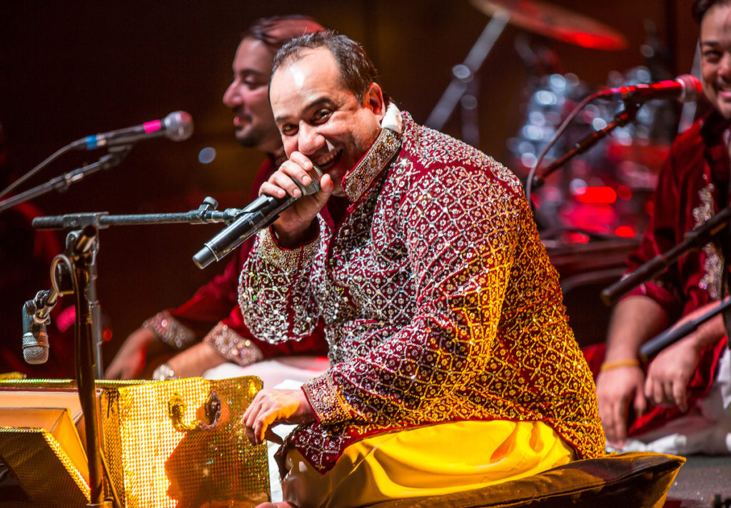 Pakistani singer Rahat Fateh Ali Khan holding microphone while sitting down and smiling