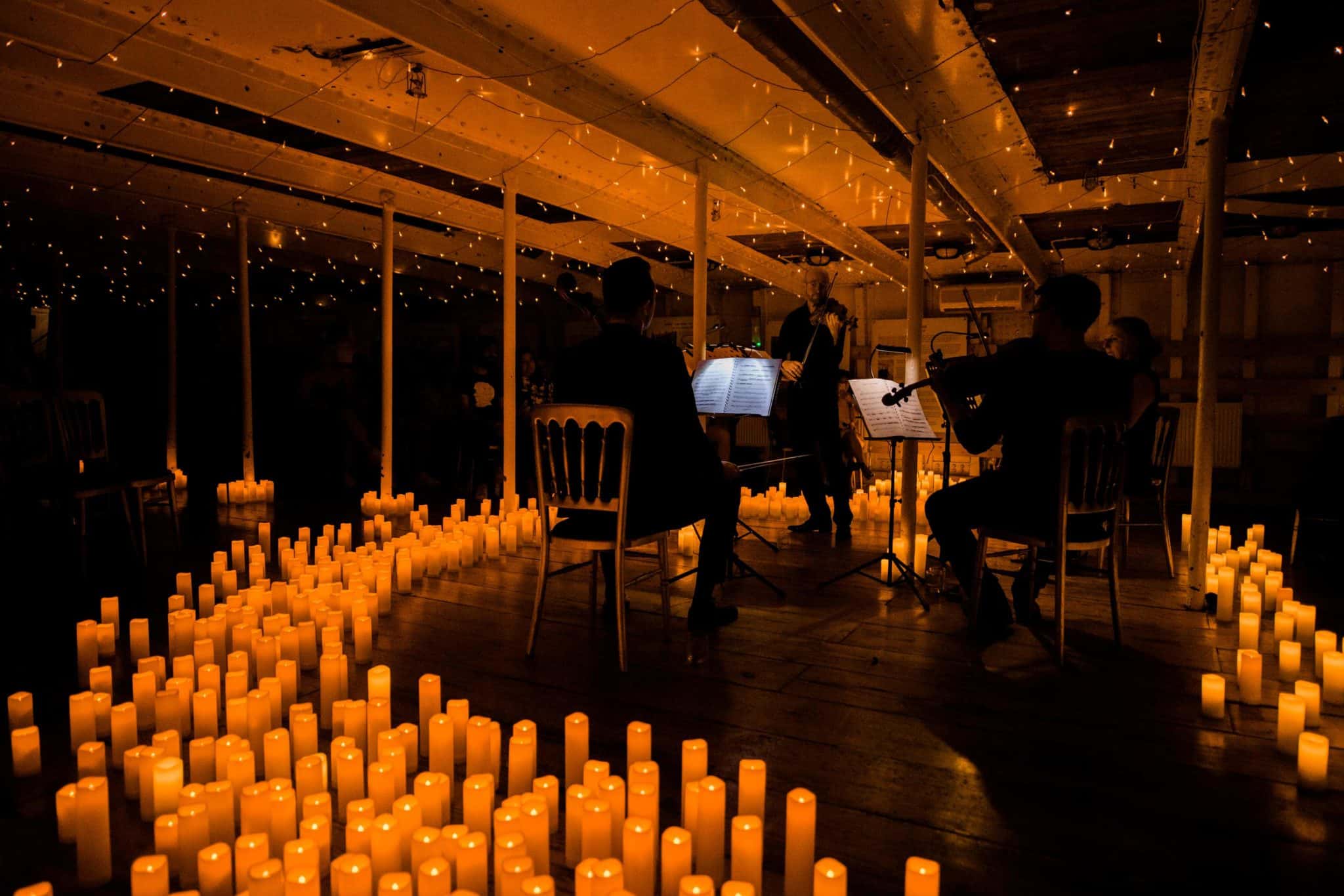 Candles covering the floor where a string quartet is performing.