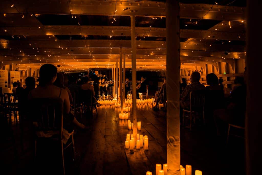 Candles on display inside the Tall Ship with a crowd seated watching a Candlelight concert.